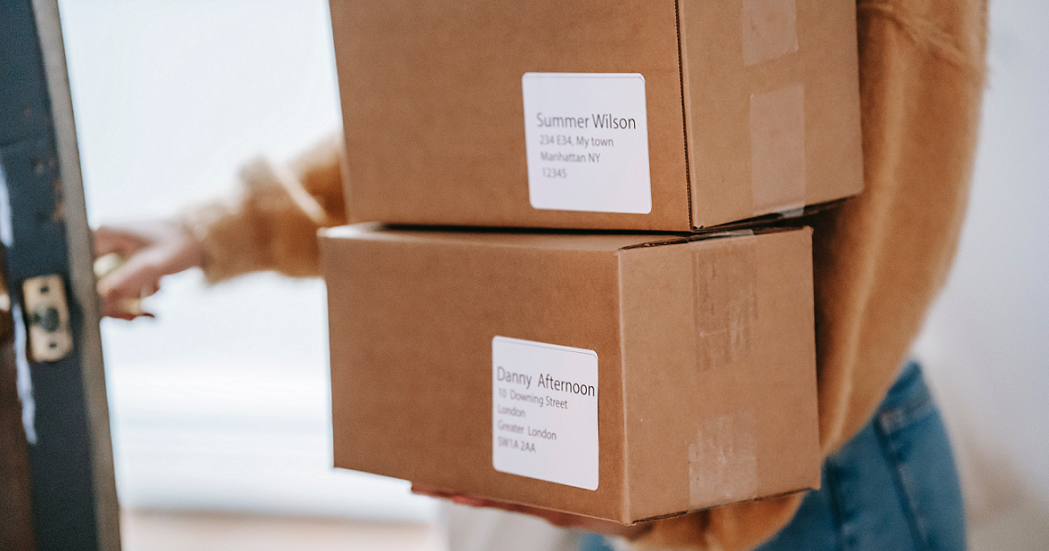 Person holding two boxes going out the door