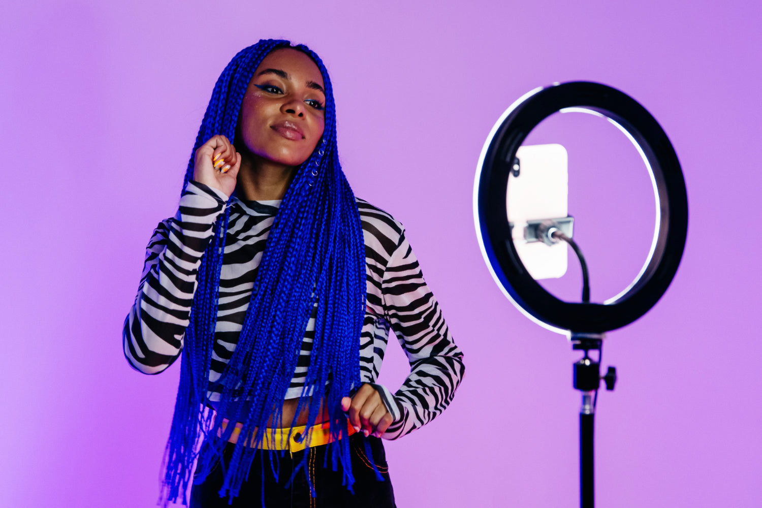 A woman performs for a mobile video using a tripod and ring light