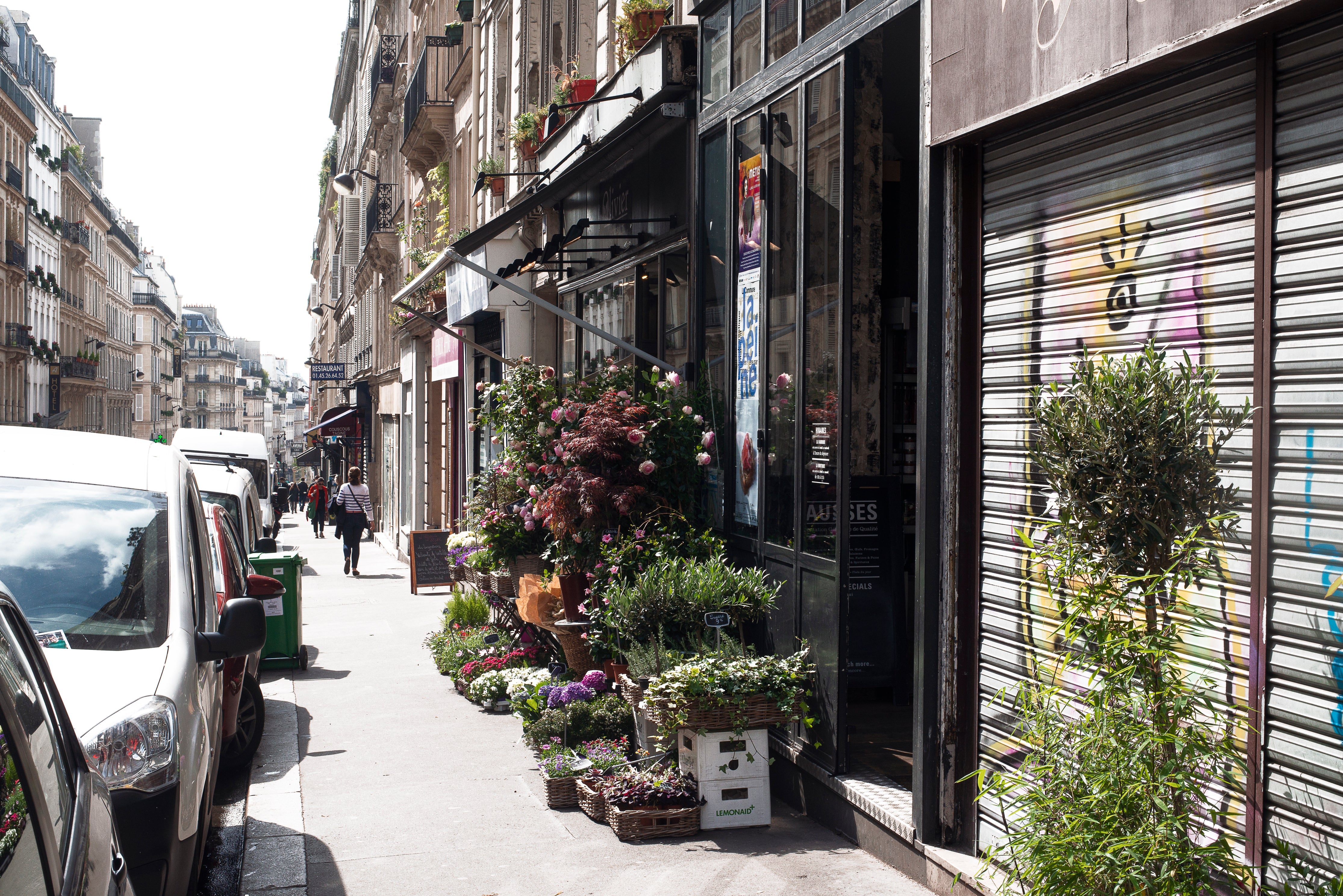 A florist displays products on a sunny street.