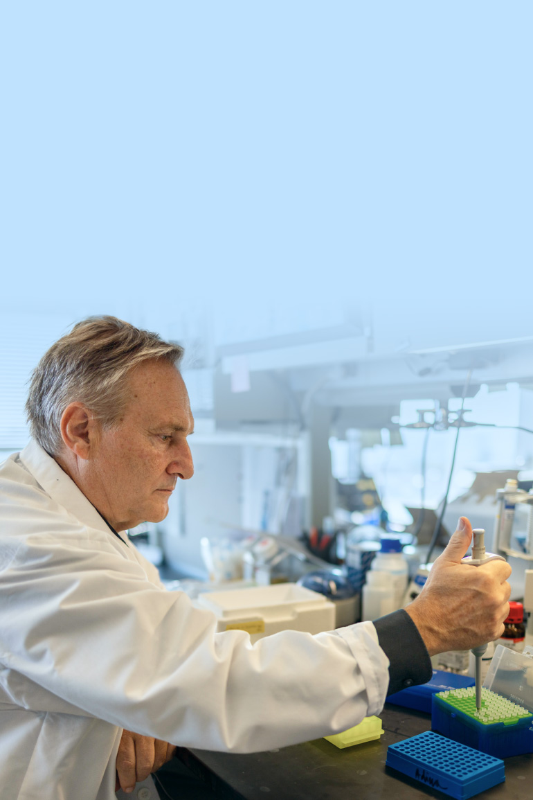 Chan Zuckerberg Biohub New York President Andrea Califano sits at a lab bench holding a pipette.