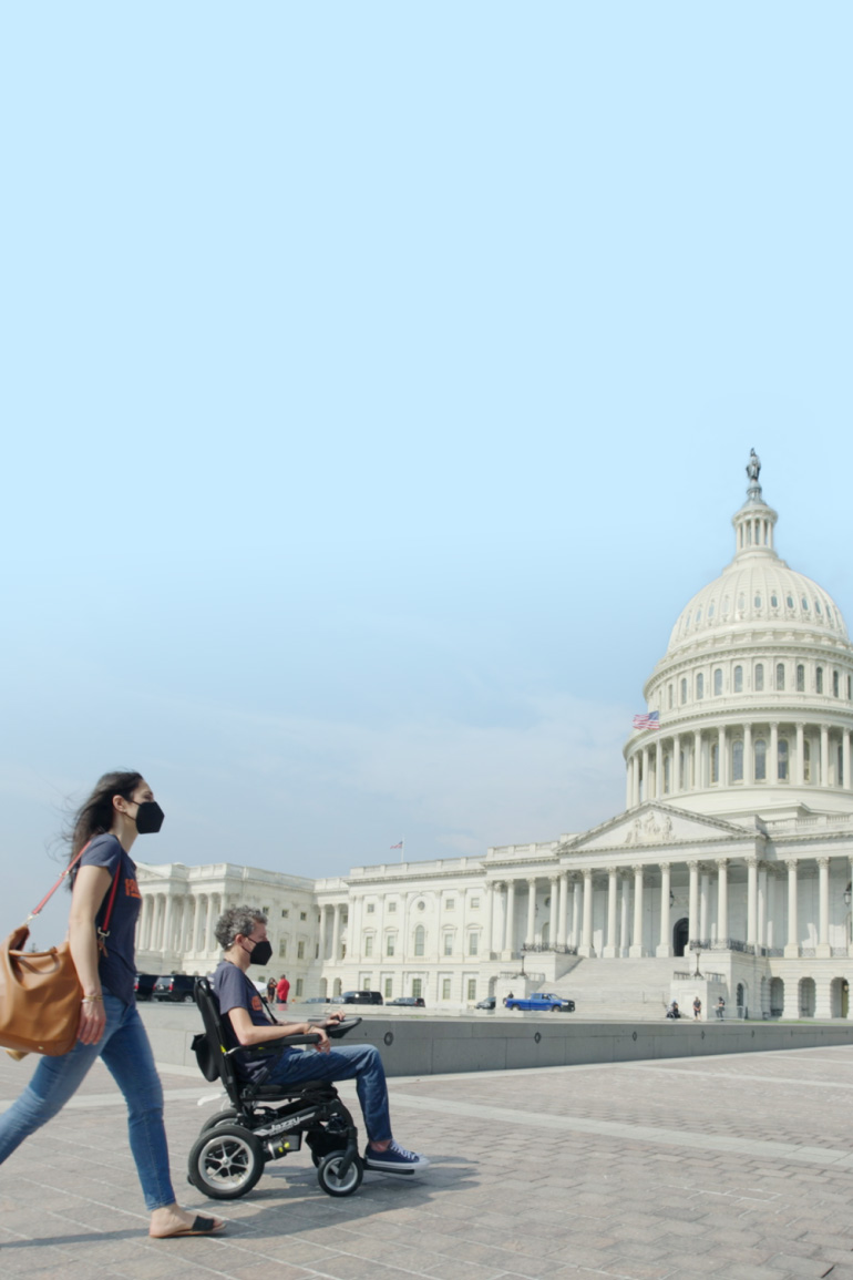 Woman pushing a man in a wheelchair in front of the Capitol Building in Washington, D.C.