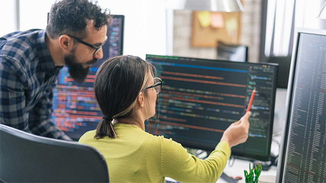 Man and woman reviewing code on computer monitor