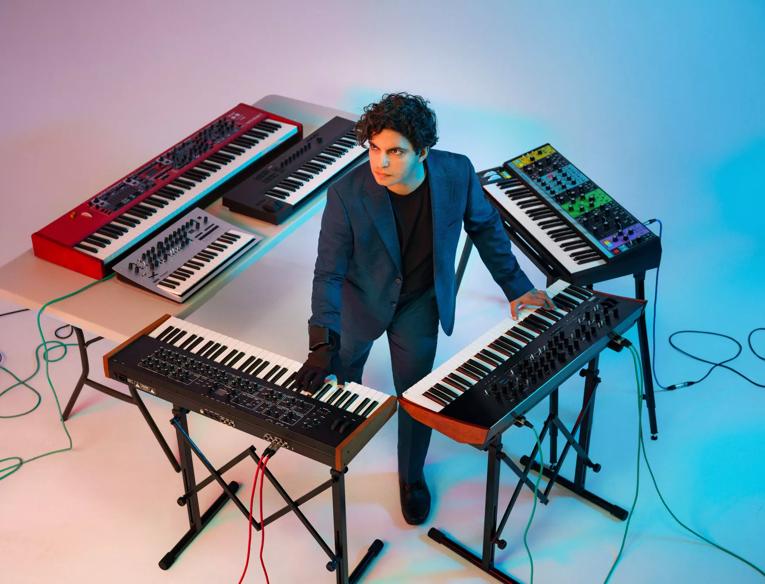 Zubin Kanga standing in the middle of multiple keyboards