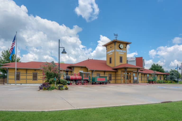 Exterior image of Dental Depot's dentist office in Midwest City, OK with a train model, yellow exterior, and red roof.