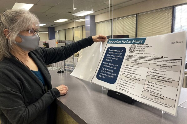 FILE - Deborah Moody, an administrative clerk at the Alaska Division of Elections office in Anchorage, Alaska, looks at an oversized booklet explaining election changes in the state, Jan. 21, 2022. An initiative aimed at repealing Alaska's ranked choice voting system still has sufficient signatures to qualify for the November 2024 ballot, attorneys for the state said Tuesday, July 23, 2024, days after a judge disqualified some of the booklets that were used to gather signatures. (AP Photo/Mark Thiessen, File)