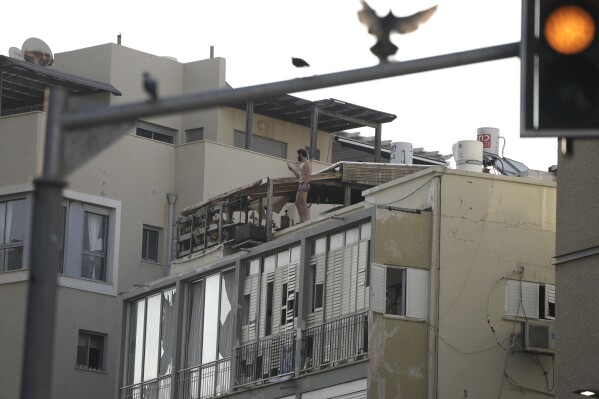A man films the scene after a deadly explosion, from his rooftop in Tel Aviv, Israel, Friday, July 19, 2024. (AP Photo/Oded Balilty)
