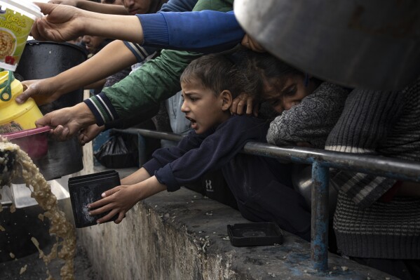 Palestinians line up for a free meal in Rafah, Gaza Strip, Thursday, Dec. 21, 2023. International aid agencies say Gaza is suffering from shortages of food, medicine and other basic supplies as a result of the two and a half month war between Israel and Hamas. (AP Photo/Fatima Shbair)