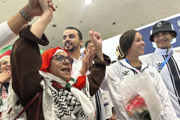 Supporters and fans cheer for Palestinian athletes like Valerie Tarazi, second right, at the Paris Charles de Gaulle airport, at the 2024 Summer Olympics, Thursday, July 25, 2024, in Roissy, north of Paris, France. (AP Photo/Megan Janetsky)