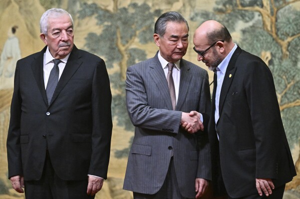 China's Foreign Minister Wang Yi, center, hosts an event for Mahmoud al-Aloul, left, vice chairman of Fatah, and Mussa Abu Marzuk, a senior member of Hamas, to meet at the Diaoyutai State Guesthouse in Beijing, Tuesday, July 23, 2024. (Pedro Pardo/Pool Photo via AP)