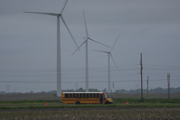 A school bus drives down a road near a field of wind turbines, Thursday, May 9, 2024, in Paxton, Ill. (AP Photo/Joshua A. Bickel)