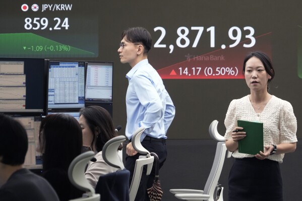 A currency trader passes by the screen showing the Korea Composite Stock Price Index (KOSPI) at the foreign exchange dealing room of the KEB Hana Bank headquarters in Seoul, South Korea, Tuesday, July 9, 2024. (AP Photo/Ahn Young-joon)