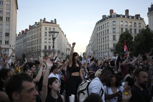 People stand in a square as they react to projected results after the second round of the legislative elections, in Lyon, central France, Sunday, July 7, 2024. Polls have closed in France, and polling projections say a coalition on the left that came together unexpectedly has won the most parliamentary seats in the pivotal runoff elections after a high turnout among voters. (AP Photo/Laurent Cipriani)