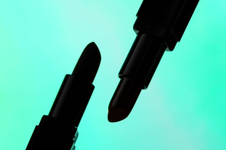 silhouette of two lipsticks on green background