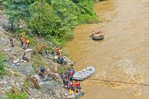 Des sauveteurs cherchant des survivants à la suite d’un effondrement de terrain ayant entraîne deux bus dans dans la rivière Trishuli, à Simaltar, dans le centre du Népal, le 12 juillet 2024