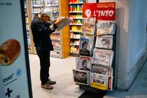 Un homme lit le journal, à Paris, le 19 août.