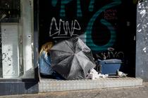 Une femme sans domicile fixe se cache sous un parapluie dans la rue, à Paris, en mars 2019.