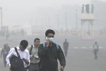 Des employés de bureau marchent dans un épais brouillard de pollution, à New Delhi, le 13 novembre 2024.