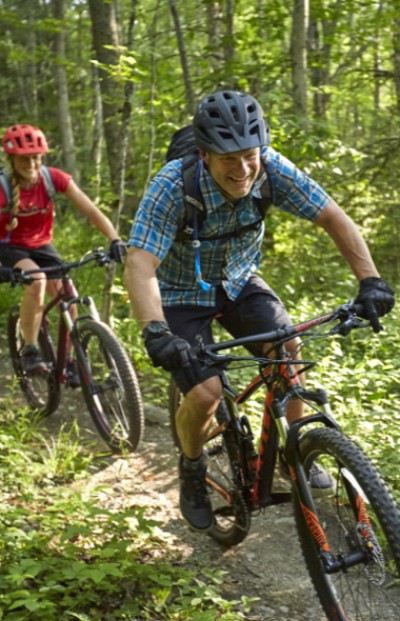 t/Wo pwoplw mountain biking on a wooded trail