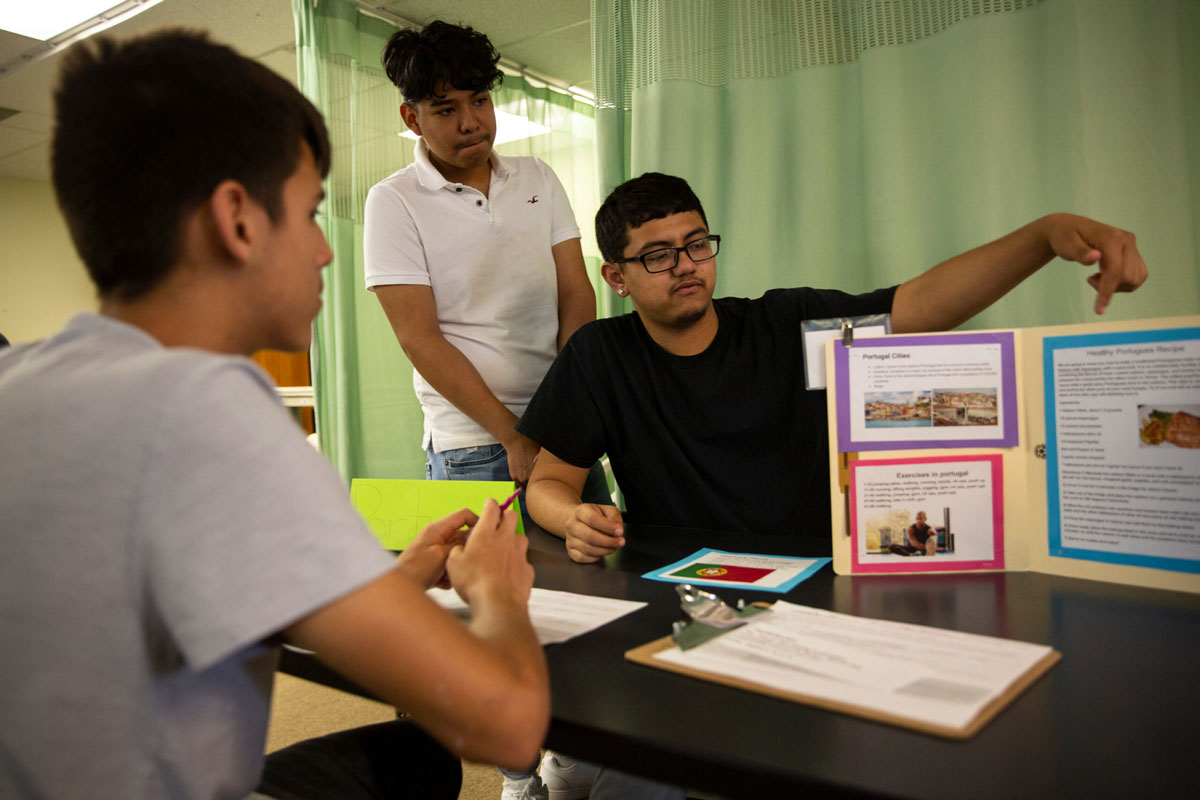 A group of three students gathered at a table doing a presentation