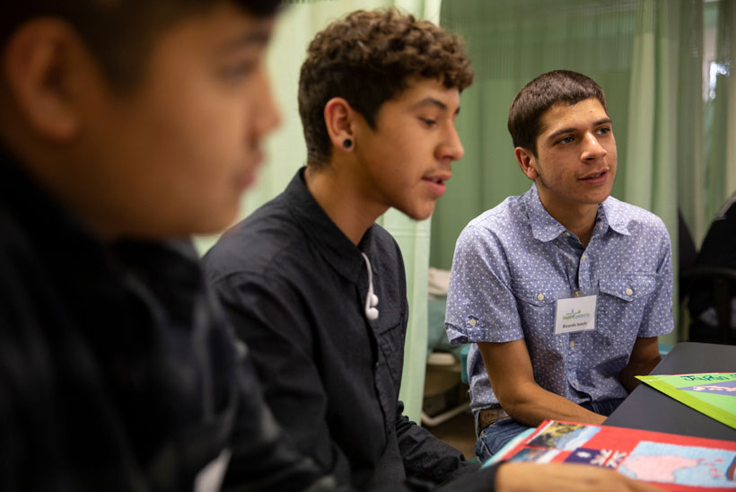 Three students sitting down engaging in conversation