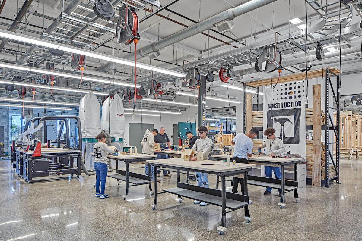 A group of construction students each at a work bench engaging in a class assignment.