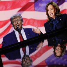 A photo of Harris and Trump on a phone screen with American flags and imagery reflected around them.