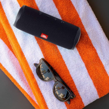 JBL portable speaker on orange and white beach towel 