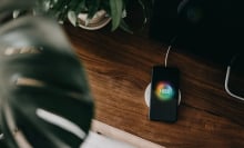 Directly above shot of a smartphone getting charged with wireless charging device on a cabinet in the living room