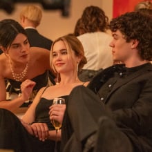 Sarah Catherine Hook and Zac Burgess sit on a couch at a fancy party in a still from "Cruel Intentions".