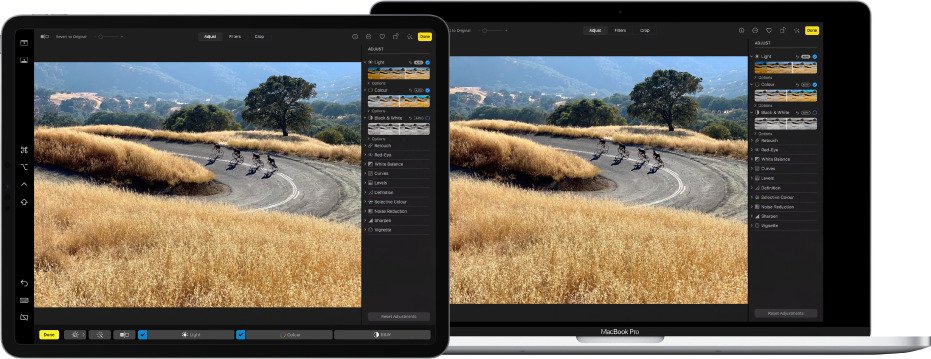 An iPad Pro next to a MacBook Pro. The Mac desktop shows a photo being edited in the Photos app. The iPad Pro shows the same photo, as well as the Sidecar sidebar at the left edge of the screen and the Mac Touch Bar at the bottom of the screen.