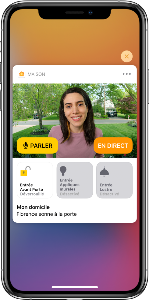 Une notification de Maison est affichée sur l’écran de l’iPhone. Elle montre la photo d’une personne à la porte d’entrée avec un bouton Parler sur la gauche. Des boutons d’accessoires pour les lumières de la porte d’entrée et de l’entrée se trouvent en dessous. Les mots « Ashley sonne à la porte » s’affichent sous les boutons d’accessoires. Le bouton Fermer s’affiche en haut à droite de la notification.