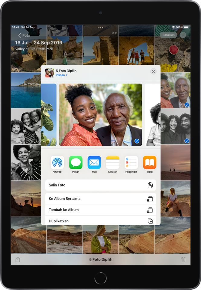 Jendela bagikan foto ada di bagian tengah layar. Foto terdapat di bagian atas jendela; satu foto dipilih, ditunjukkan dengan tanda centang. Baris di bawah foto menyarankan kontak terbaru untuk berbagi. Di bawah kontak yang disarankan terdapat opsi berbagi. Dari kiri ke kanan terdapat AirDrop, Pesan, Mail, Catatan, Pengingat, dan Buku. Di bagian bawah layar berbagi terdapat baris tindakan. Dari bagian atas ke bawah, Salin Foto dan Tambahkan ke Album Bersama ditampilkan.