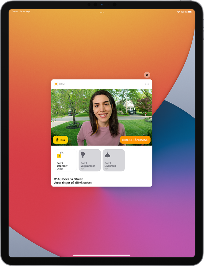 En notis från Hem visas på iPad-skärmen. Den visar bilden på en person vid ytterdörren. Till vänster finns knappen Tala. Under det finns tillbehörsknappar för ytterdörren och entréljus. Hemmets adress visas längst ned tillsammans med orden ”Iris ringer på dörrklockan”. Högst upp till höger på notisen finns en stängningsknapp.