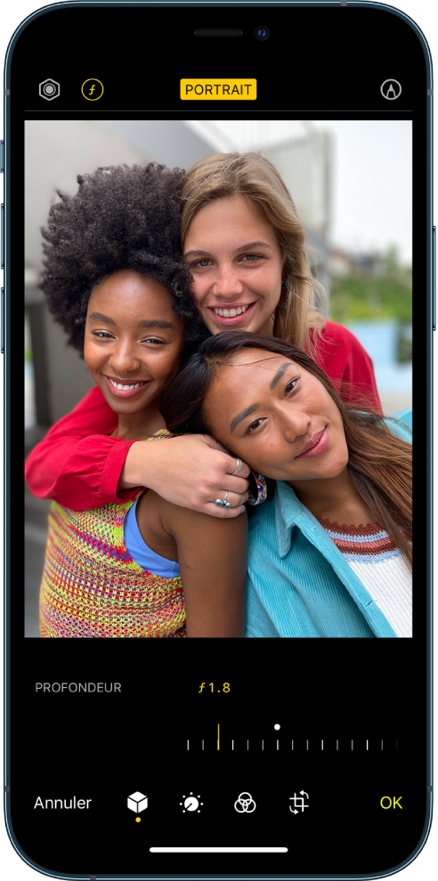 L’écran Modifier d’une photo prise en mode Portrait. En haut à gauche de l’écran se trouvent les boutons « Intensité de l’éclairage » et « Réglage de la profondeur ». En haut, au centre de l’écran, le bouton Portrait est activé et en haut à droite se trouve le bouton Modules. La photo est au centre de l’écran ; sous celle-ci se trouve un curseur permettant d’ajuster le réglage de la profondeur. Sous ce curseur se trouvent, de gauche à droite, les boutons Annuler, Portrait, Ajuster, Filtres, Recadrer et OK.