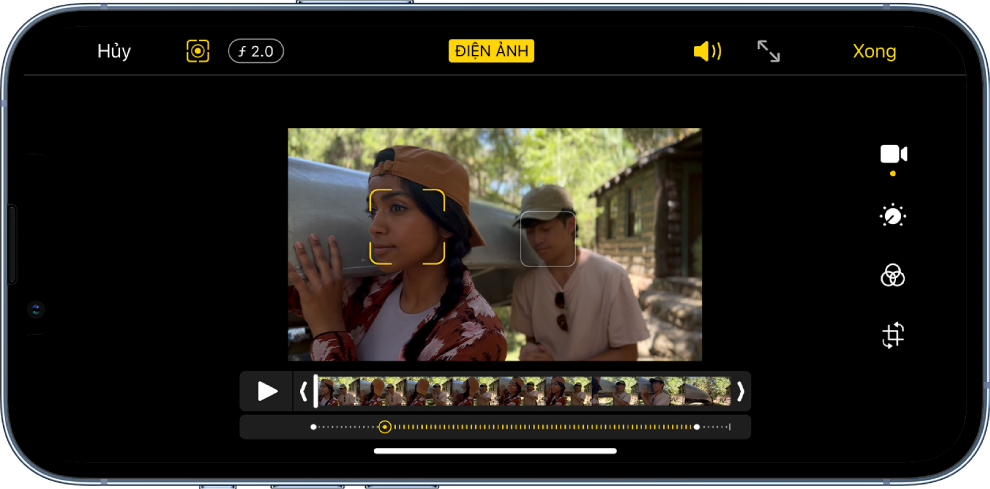 Màn hình Sửa của video chế độ Điện ảnh ở hướng ngang. Ở trên cùng bên trái của màn hình là nút Hủy, nút Điện ảnh thủ công và nút Điều chỉnh chiều sâu. Ở trên cùng ở giữa của màn hình, nút Điện ảnh được chọn. Ở trên cùng bên phải của màn hình là nút Âm lượng, nút Chuyển sang toàn màn hình và nút Xong. Video ở giữa màn hình và có một khung hình xung quanh chủ thể lấy nét. Bên dưới video là trình xem khung hình hiển thị điểm trong video mà lấy nét chủ thể thay đổi. Các công cụ sửa nằm ở bên phải của màn hình, từ trên xuống dưới: Video, Điều chỉnh màu, Bộ lọc và Cắt xén.