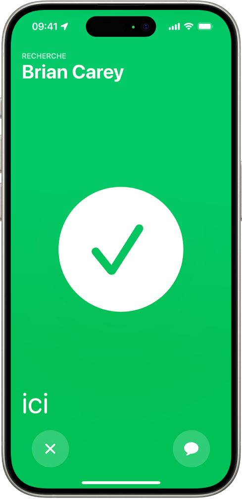L’écran de l’iPhone est vert, avec une coche de grande taille au milieu. Le nom de la personne localisée apparaît en haut à gauche. Le mot « ici » se trouve en bas à gauche et indique que les deux personnes se sont trouvées.