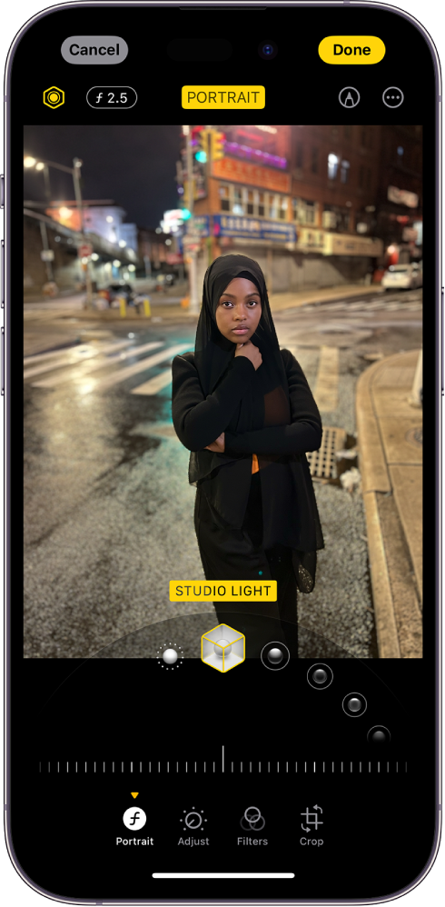 Portraito redagavimo ekranas. Nuotrauka yra ekrano centre, o po nuotrauka yra „Portrait Lighting“ parinktys. Pasirinkta parinktis „Studio Light“. Žemiau yra slankiklis, kuriuo koreguojamas efekto lygis. Po slankikliu iš kairės į dešinę išdėstyti „Portrait“, „Adjust“, „Filters“ ir „Crop“ mygtukai. Pasirinktas mygtukas „Portrait“.