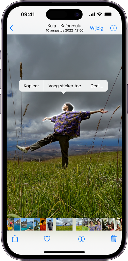 De Foto's-app is geopend met een foto van iemand. Deze persoon is geselecteerd en de optie 'Voeg sticker toe' is beschikbaar in het menu erboven.