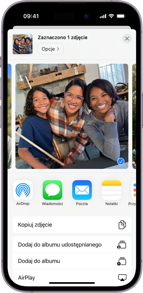 Zaznaczone zdjęcie wyświetlone w górnej części ekranu iPhone’a. Poniżej widoczne są opcje udostępniania. AirDrop, Wiadomości, Poczta oraz Notatki. Poniżej opcji udostępniania znajdują się inne czynności, które można wykonać ze zdjęciem, takie jak Kopiuj zdjęcie, Dodaj do albumu udostępnianego, Dodaj do albumu oraz AirPlay.
