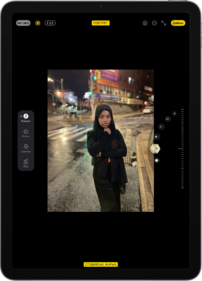 «Портрет» режиміндегі фотоның «Өңдеу» экраны. Фото экранның ортасында орналасқан, ал экранның оң жағында «Портреттік жарықтандыру» опциялары бар. «Студиялық жарық» параметрі таңдалған және әсер деңгейін реттеу үшін слайдер бар. Экранның сол жағындағылар — «Портрет», «Реттеу», «Сүзгілер» және «Кесу» түймелері. «Портрет» түймесі таңдалған.