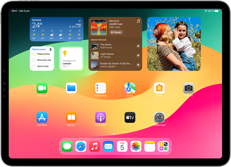 Hemskärmen på iPad. Överst på skärmen finns widgetar för Väder, Påminnelser, Hem, Musik och Bilder. Widgetarna för Påminnelser, Hem och Musik visar interaktiva funktioner.