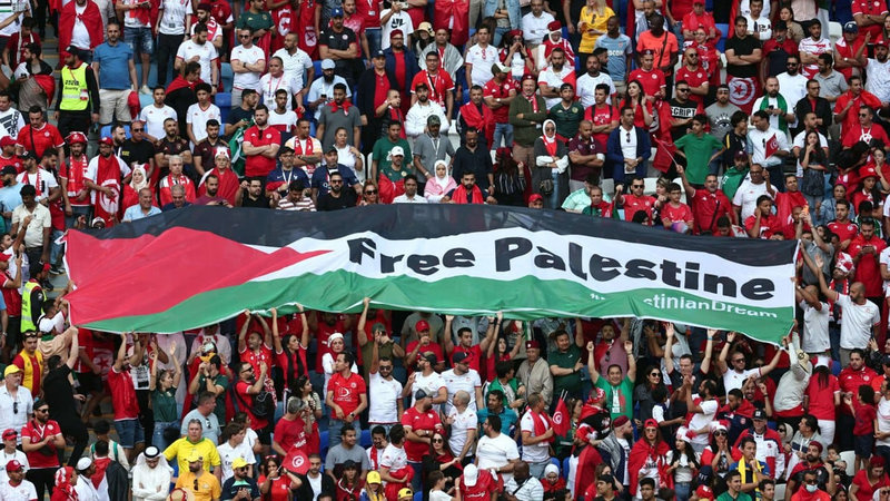 A group of people holding a large free Palestine flag.