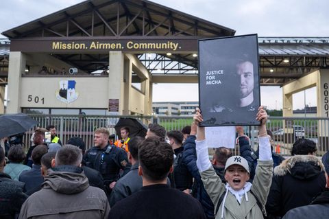 Demonstranten vor der Airbase halten Schilder hoch