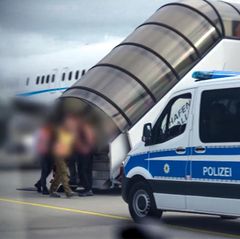 Die Passagiere werden von Polizisten in das Flugzeug begleitet