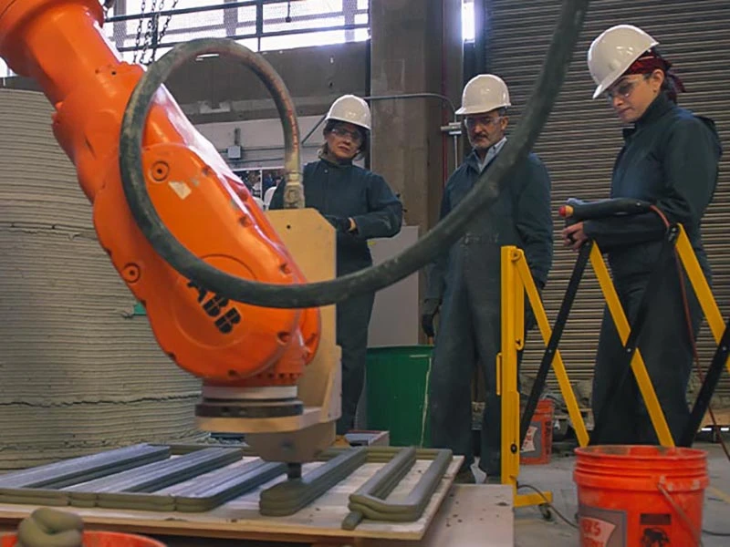 Penn State researchers viewing a machine print cement