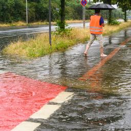 Ein Mann steht nach einem Platzregen barfuß auf dem Fußgängerweg