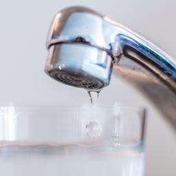 Aus einem Wasserhahn läuft Trinkwasser in ein Wasserglas.