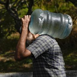 Ein Mann trägt in Venezuela einen Wasserkanister.