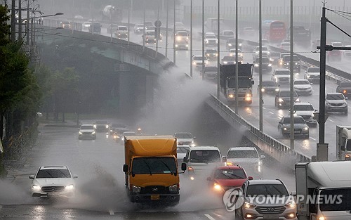 资料图片：7月8日，在光州市西区，倾盆大雨导致武珍大路多处积水，不少来往车辆溅起水浪。 韩联社