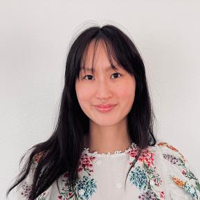 Image of female with black hair wearing a white top with colorful patterns.